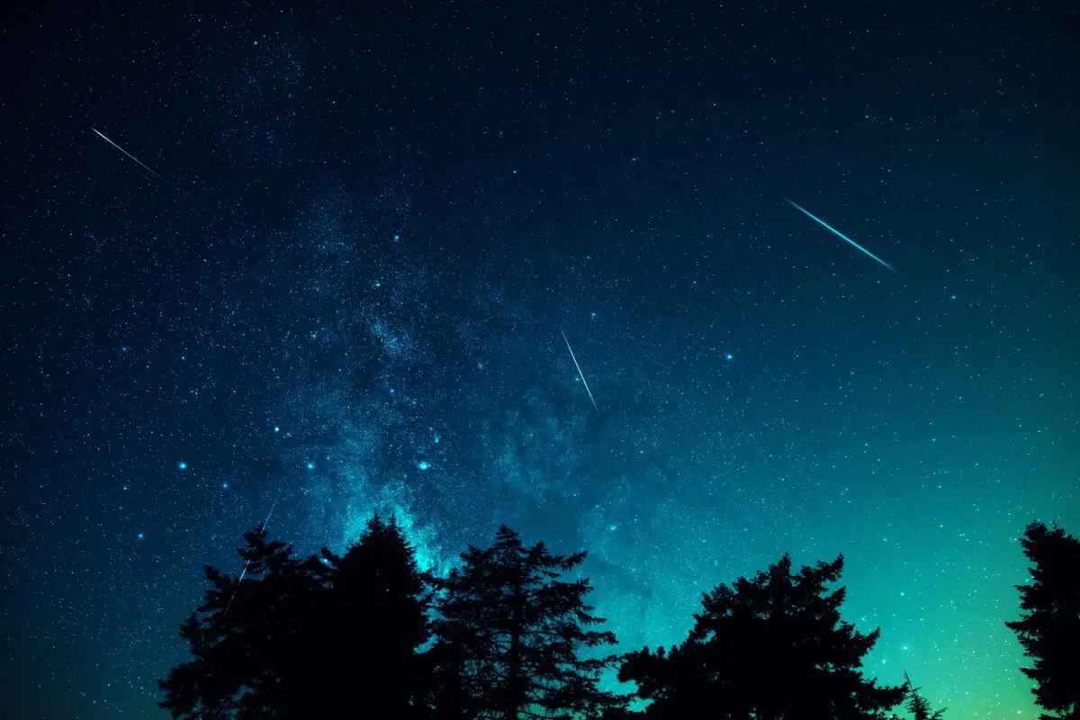 Stars shoot across a glowing night sky.